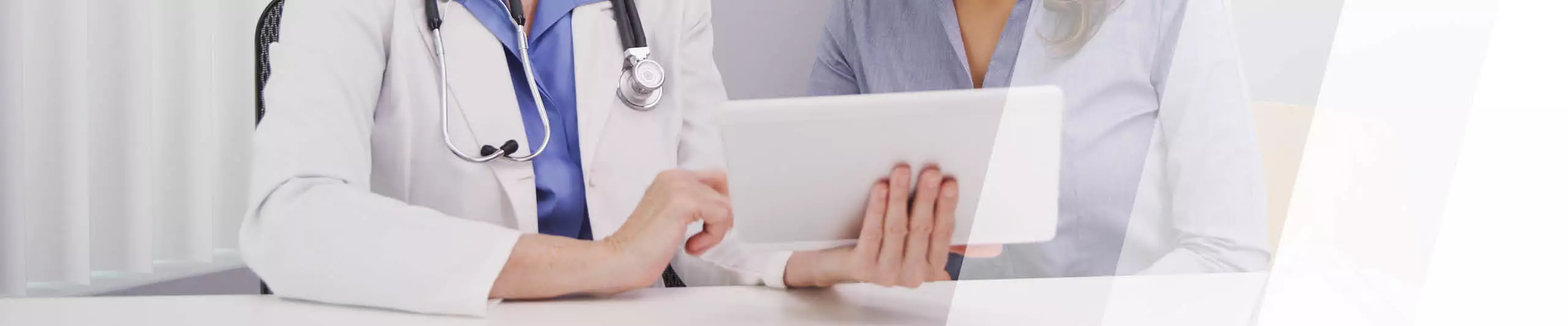 Betriebsärztin zeigt Patientin etwas auf einem Tablet 