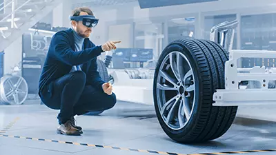 Mann mit VR-Brille konstruiert ein virtuelles Fahrzeug-Chassis