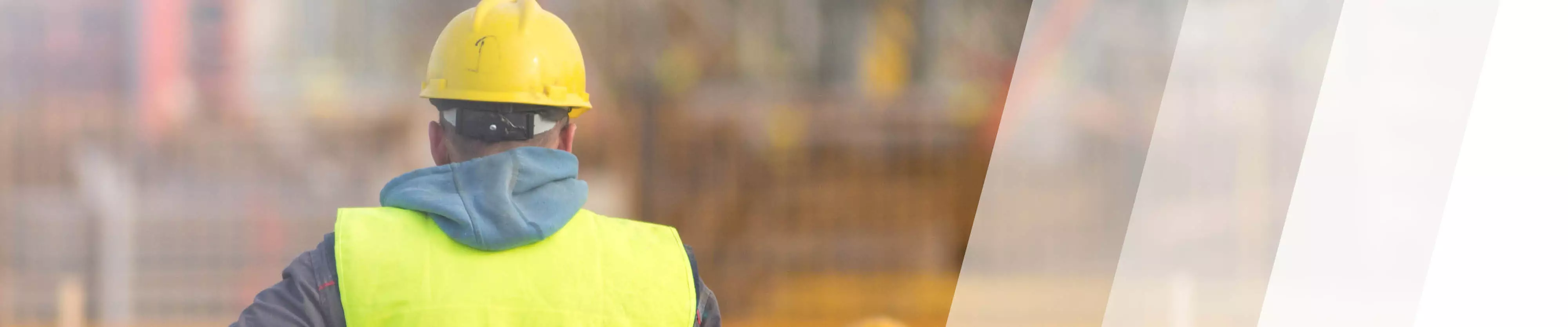 Arbeiter mit Schutzweste und Schutzhelm von hinten