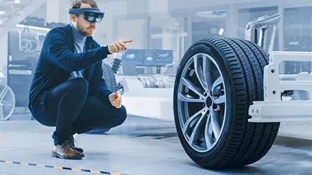Mann mit VR-Brille konstruiert ein virtuelles Fahrzeug-Chassis